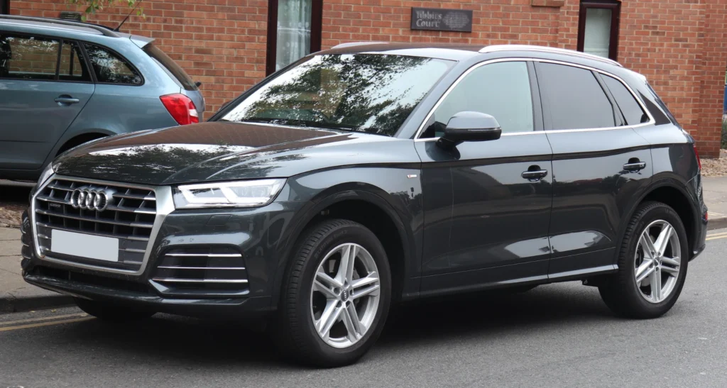 Dark gray Audi Q5 S line parked on a street, viewed from the front three-quarter angle.