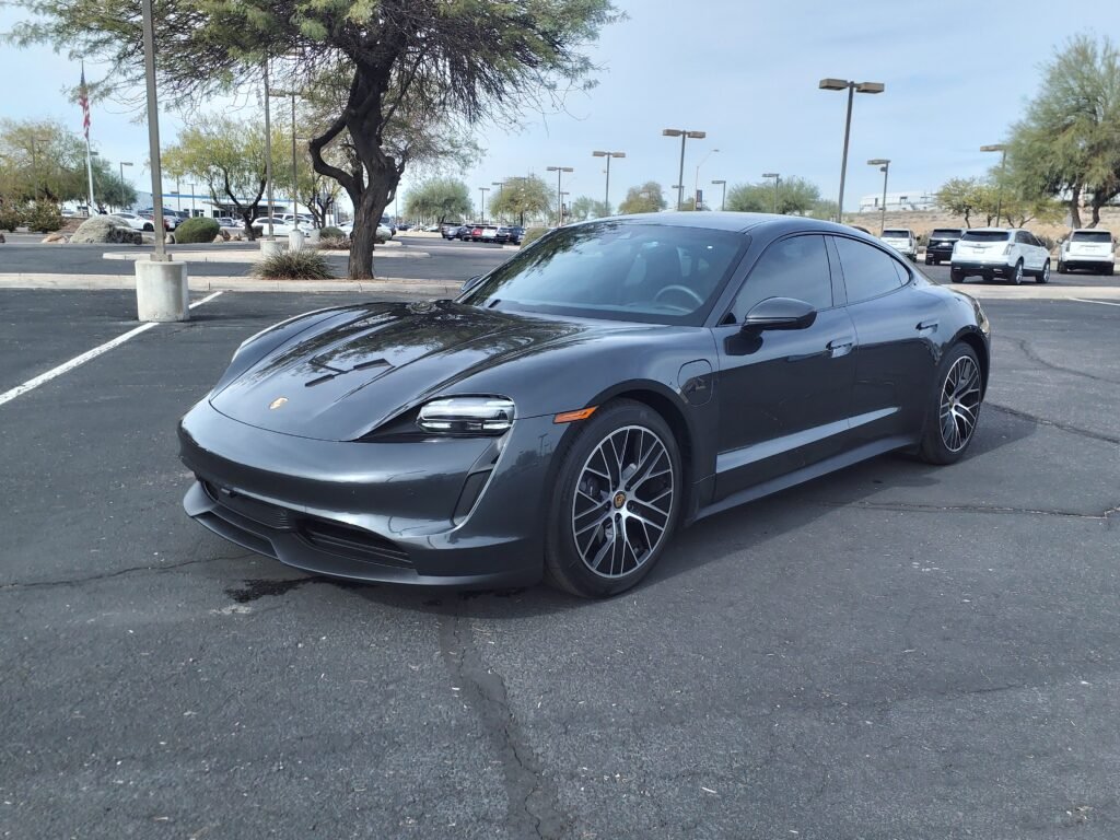 Dark gray 2022 Porsche Taycan parked in a dealership lot in Scottsdale, Arizona.