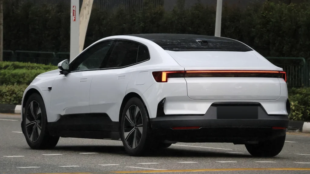 Side profile of a silver Polestar 4 parked beside a rocky landscape.